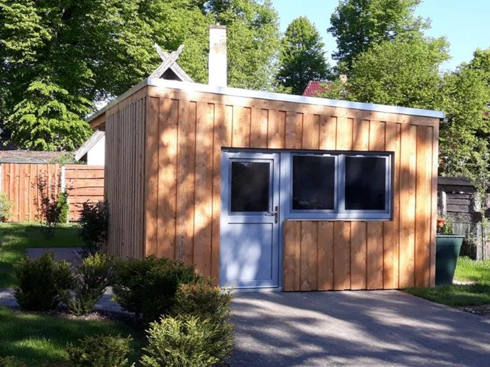 Die neu errichtete Holzhütte der Lewitz Rösterei mit blauer Tür im Sommer